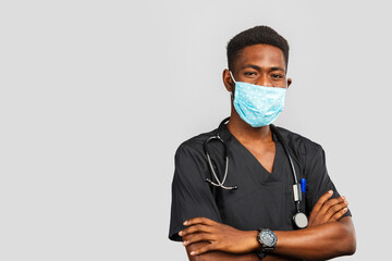 Confident male doctor. Cheerful african doctor in medical mask standing against gray background