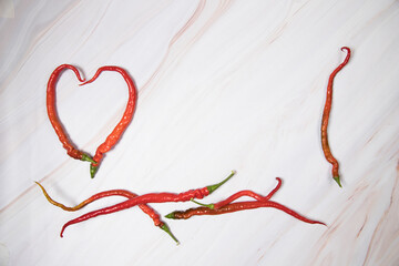 The heart is made of hot red peppers, a group of peppers on a light background. The concept of spicy food love.Place for a copy space