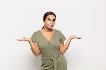 pretty young woman feeling puzzled and confused, unsure about the correct answer or decision,...
