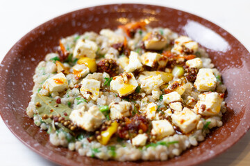 Smoky Marinated Feta in olive oil with spices and green buckwheat on brown plate close up