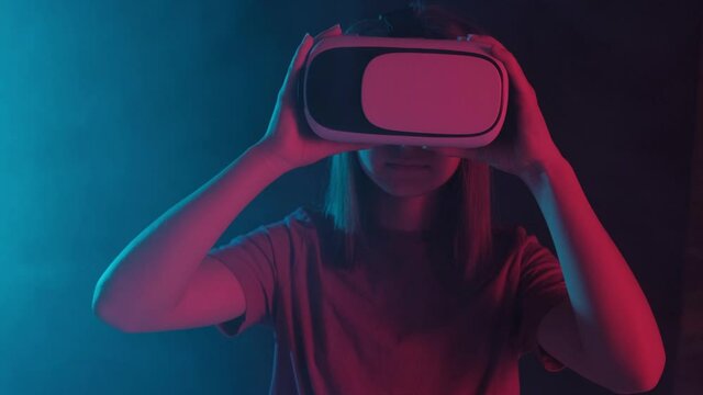 Portrait of a young beautiful girl in virtual reality glasses on a black background.