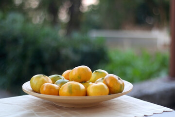 Wooden bowl with tangerines in a garden. Selective focus.