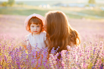 Mother hugs daughter at sunset in the lavender field.