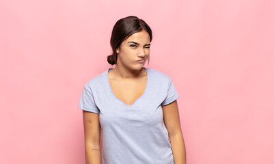 pretty young woman looking happy and friendly, smiling and winking an eye at you with a positive...