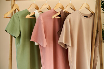 color basic clothes hanging on wooden hangers. fabric and textile close up on shirts