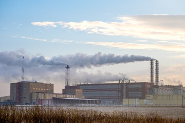 Fototapeta na wymiar Smoke stacks factory emitting gases into the atmosphere. Smoke from factory over city in sunrise