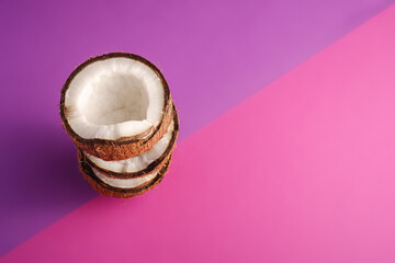 Stacked coconut fruits on violet and purple plain background, abstract food tropical concept, angle view copy space