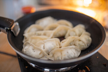 Dumplings on a Frying Pan with a Blurry Fireplace in the Background