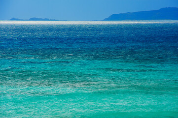 Fototapeta premium ｴﾒﾗﾙﾄﾞｸﾞﾘｰﾝに輝く久米島の海と青い岬