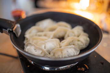 Dumplings on a Frying Pan with a Blurry Fireplace in the Background