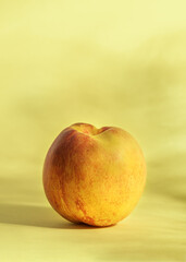 Ripe nectarine on a yellow background with shadows.