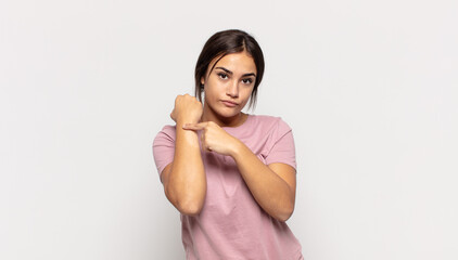 pretty young woman looking impatient and angry, pointing at watch, asking for punctuality, wants to...