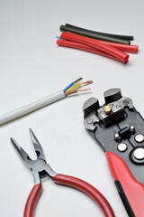 wire stripper, shielded three-core wire and heat shrink tubing on a white background. close-up