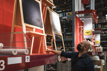 Masked man buying chalkboard to teach distance learning.