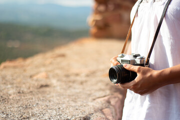 Woman holds a vintage camera hanging from her neck ready to shoot