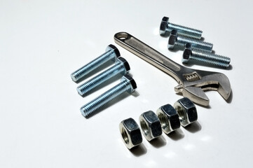 screw-nut of different sizes, bolts and adjustable spanner. White background.