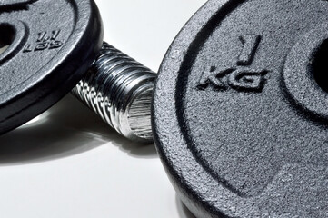 bar and black discs of a collapsible dumbbell with weight designation. close-up.
