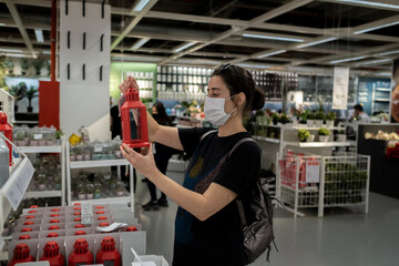 Young lady in a mask shopping at the grocery store for celebration and authentic decor.
