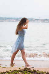 Young girl with a turquoise dress walking through the beach of Saint Jean de Luz; Basque Country.