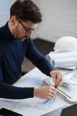 Architect working in office with blueprints.Engineer inspect architectural plan, sketching a construction project.Portrait of handsome bearded man sitting at workplace. Business construction concept.