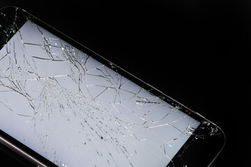 glowing broken smartphone screen close up on dark background.