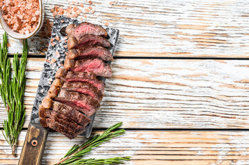 Grilled ramp cap steak on a meat cleaver. White wooden background. Top view.  Copy space