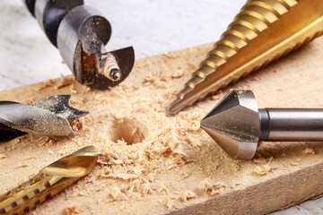 Drilling in wood with steel drills and countersinks. Minor carpentry work in the workshop. - obrazy, fototapety, plakaty