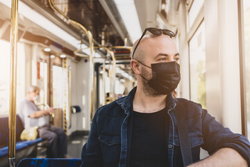 Handsome young man in black mask is traveling by subway.