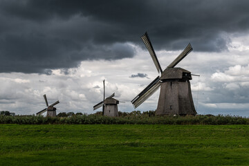 Three windmills with dark sky above
