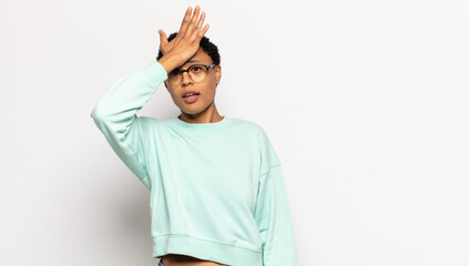 young afro woman raising palm to forehead thinking oops, after making a stupid mistake or...