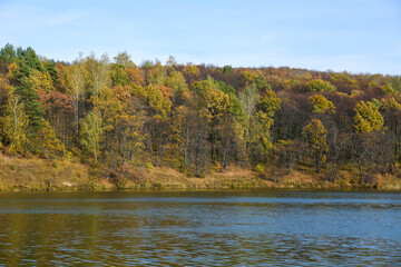 autumn landscape of lake and orange forest on the slope. panoramic view of the forest river on a sunny autumn day