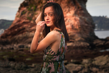 Young girl with a colorful dress posing at a rocky cove at the basque coast.