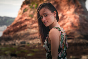 Young girl with a colorful dress posing at a rocky cove at the basque coast.