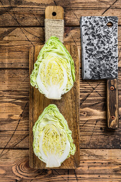 Raw Cutting Pointed white cabbage head on a cutting board. Wooden background. Top view