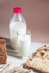 A glass of milk, sliced rustic bread and jam, on a white wooden board. Healthy food and farming concept
