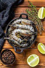 Fresh tiger shrimps, prawns with spices and herbs in a pan. wooden background. Top view