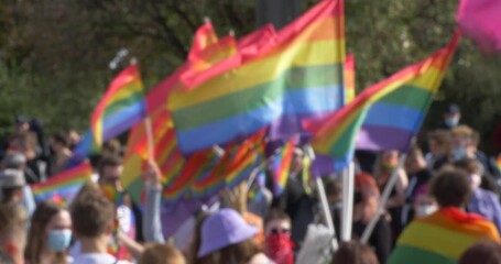 Blured unfocused crowd people with rainbow LGBT flags - Powered by Adobe