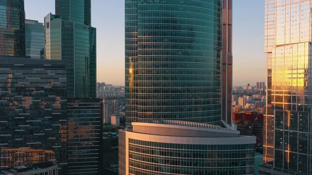 Moscow city glass skyscrapers drone pan shot left to right, close to the buildings windows, sun reflection in the windows. Moscow International Business Center at the sunset, evening