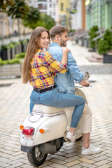Man andwoman riding a stylis retro scooter