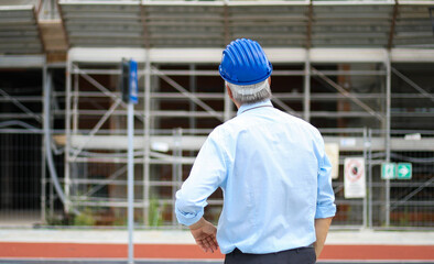 Back view of an engineer looking at a building in construction