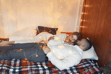 Couple with a garland. Lady in a white pajamas. Man in a white shirt.