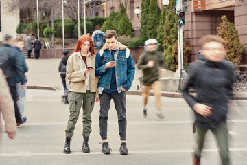 Full length shot of two teenagers totally absorbed in their smartphones, ignoring each other while standing together on the city street