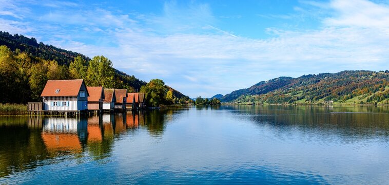 View on big, Grosser Alpsee lake by Immenstadt im Allgau with wooden hauses, blue sky. Bavaria, Germany.