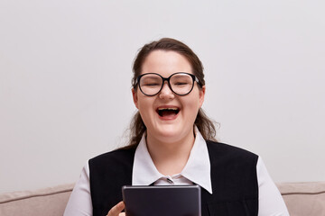 Laughing young woman with a tablet in her hands. Strict form of clothing.