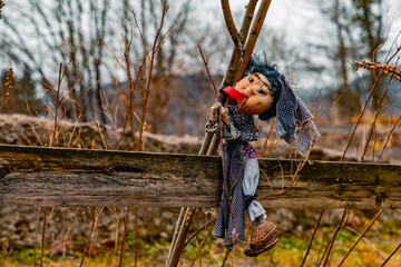 Halloween concept poster of poor abandoned doll hanging on old garden palisade outdoor environment space October time 31th eve