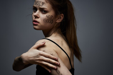 upset woman with offensive writing on her body on gray background touching herself with hands cropped view
