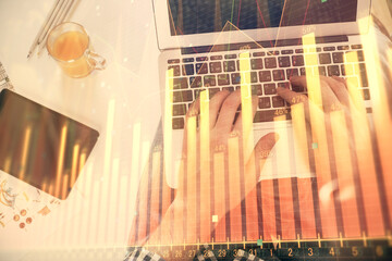 Double exposure of man's hands typing over laptop keyboard and forex chart hologram drawing. Top view. Financial markets concept.