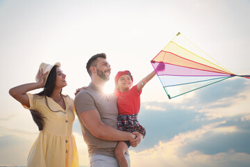 Happy parents and their child playing with kite on sunny day. Spending time in nature