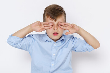 Naklejka premium Portrait of a boy, covering his eyes with his hands. Isolated on white background.