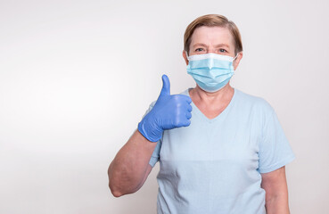Elderly woman showing thumbs up while wearing mask and gloves